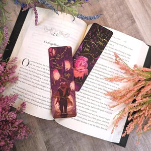 May include: Two rectangular bookmarks featuring dark purple and black backgrounds with gold foil accents. One bookmark shows a figure in a dark coat with the text 'I'm going to take you somewhere safe.' The other shows a figure with the text 'I know, Jacks.'