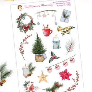 May include: A sheet of Christmas themed planner stickers featuring a wreath, a Christmas tree, candles, a poinsettia, a cup of hot chocolate, a star, a bell, a gift, a horn, and holly. The stickers are on a white background and are printed with watercolour illustrations.