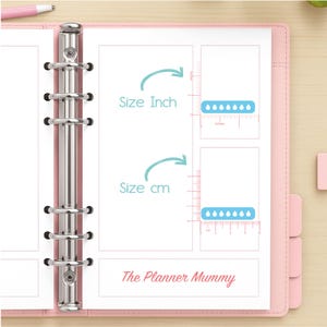 May include: Pink planner with silver binder rings, open to a page with size comparison charts in inches and centimeters. The text "Size Inch" and "Size cm" are displayed. The bottom of the page reads "The Planner Mummy". A pink pen is visible.