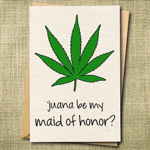 Peut inclure: Carte de vœux avec une illustration d'une feuille de cannabis verte et le texte "juana be my maid of honor ?" sur un fond crème. La carte est dans une enveloppe marron, sur un fond texturé beige.