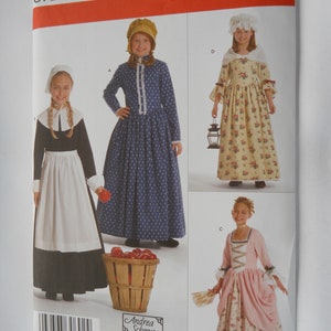 May include: Simplicity sewing pattern number 3725 for girls' colonial dresses in sizes K5, 7, 8, 10, 12, and 14. The pattern includes three different dress styles: a blue and white polka dot dress with a white apron, a yellow and white floral dress with a white lace collar, and a pink and white floral dress with a white lace collar.