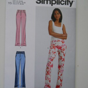May include: Simplicity sewing pattern number S9892 for women's pants. The pattern includes three different styles: a pair of pink pants, a pair of blue jeans, and a pair of floral print pants. The pattern is for sizes US 18-26, Talla Euro 44-52, and Taille FR 46-54.