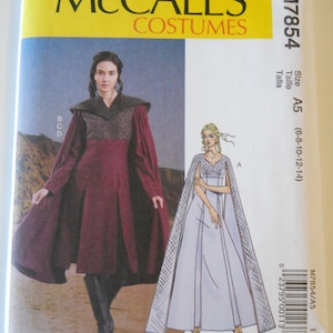 May include: A sewing pattern for two costumes. The first costume is a long, burgundy dress with a cape. The second costume is a long, white dress with a cape. The pattern is for sizes 6-8-10-12-14. The pattern is from McCall's Costumes and is labeled M7854.