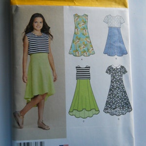May include: Simplicity sewing pattern number 8065 for girls' sizes 8-16. The pattern includes four different dress styles: a sleeveless dress with a floral print, a short-sleeved dress with a white top and a blue denim skirt, a sleeveless dress with a striped top and a green skirt, and a short-sleeved dress with a white collar and a floral print.