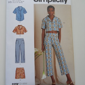 May include: Simplicity sewing pattern S9610 for a cropped top and pants. The pattern includes instructions for making a short-sleeved shirt, a pair of pants, and a cropped top. The pattern is designed for sizes 6-14.