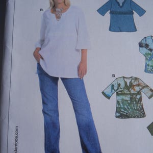 May include: A sewing pattern envelope featuring a white tunic with three-quarter length sleeves and a V-neckline, paired with blue jeans. The illustration shows variations of the tunic in solid blue and a green patterned fabric with the text TUNIC.