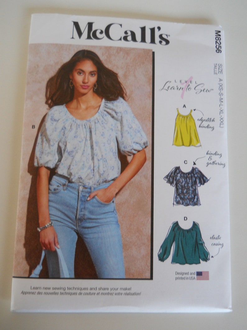May include: McCall's sewing pattern M8256, Learn to Sew, size A (XS-S-M-L-XL-XXL), featuring a blue and white floral blouse with a gathered neckline, and three variations of the blouse with different neckline finishes: a yellow blouse with an edgestitch binding, a blue and white floral blouse with a binding and gathering, and a teal blouse with an elastic casing.