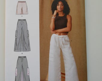 May include: Simplicity sewing pattern number S9956 for pants. The pattern includes three different styles of pants: wide-leg pants with a tie waist, wide-leg pants with a tie waist and cargo pockets, and cropped pants with a tie waist. The pattern is for sizes XS-XXL.