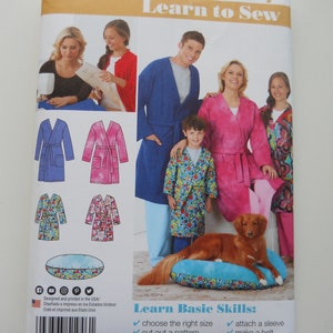 May include: Simplicity sewing pattern number 1946, Learn to Sew, with instructions for making a robe, a dog bed, and a patch pocket. The pattern includes basic sewing skills like choosing the right size, cutting out a pattern, stitching seams, attaching a sleeve, making a belt, and inserting a zipper.