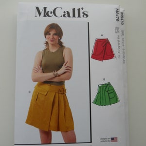 May include: McCall's sewing pattern M8479 for a skirt. The pattern includes instructions for three different styles of skirts: a red skirt with a wrap detail, a green skirt with a pleated detail, and a yellow skirt with a pleated detail and a belt. The pattern is designed and printed in the USA.