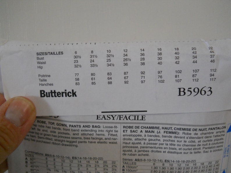 Może przedstawiać: Papierowy wz&oacute;r wykroju Butterick, model B5963, z tabelami rozmiar&oacute;w dla obwodu biustu, talii i bioder w cm. Wz&oacute;r zawiera instrukcje dotyczące sukienki, topu, szlafroka, spodni i torby.