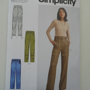 May include: A sewing pattern for women's pants. The pattern includes three different styles of pants: a pair of khaki cargo pants, a pair of olive green cargo pants, and a pair of blue denim cargo pants. The pattern is for sizes US 18-26, TALLA EURO 44-52, TAILLE FR 46-54.