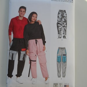 May include: A sewing pattern for pants, featuring two different styles. The first style is a pair of camouflage cargo pants, the second style is a pair of pink cargo pants. The third style is a pair of gray cargo pants with blue accents. The pattern is labeled "N6745" and "Size/Taille/Talla A".