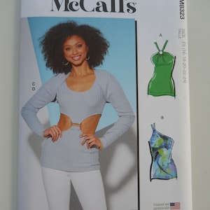 May include: A sewing pattern for a top with multiple view options. The pattern includes instructions for making a green top with a knotted detail, a blue and green tie-dye top, and a light blue top with cutouts. The pattern is for sizes F5 (16-18-20-22-24).