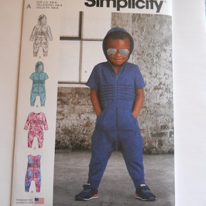 May include: Simplicity sewing pattern S9486 for a child's jumpsuit. The pattern includes four different styles: A, B, C, and D. The pattern is designed and printed in the USA.