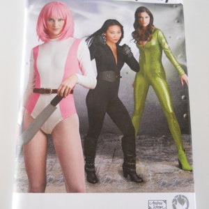 May include: A sewing pattern for three different costumes. The pattern is for sizes 16-24, European sizes 42-50, and French sizes 44-52. The pattern is from Simplicity and is number 8670 U5. The costumes are a white and pink jumpsuit, a black jumpsuit, and a green jumpsuit.