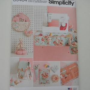 May include: A sewing pattern for a set of storage organizers for sewing supplies. The pattern includes instructions for making a pincushion, a needle book, a small pouch, a larger pouch, a cone-shaped organizer, and a roll-up organizer. The pattern is from Simplicity and is for one size.