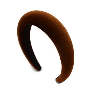 May include: A brown velvet headband with a wide, curved shape.