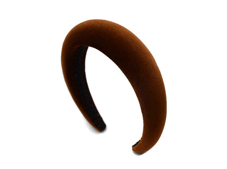 May include: A brown velvet headband with a wide, curved shape.
