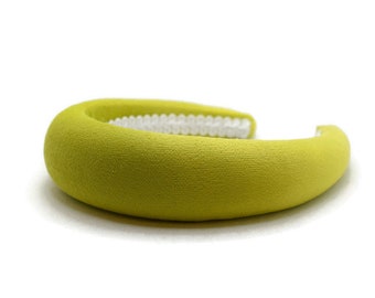 May include: A bright yellow headband made of soft fabric. The headband is curved and has a smooth, slightly textured surface.