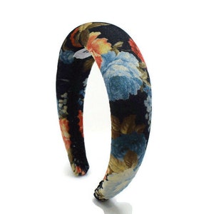 May include: A black headband with a floral print featuring blue, orange, and yellow flowers. The headband is thick and padded.