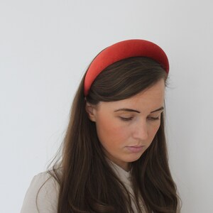 Puede incluir: Una mujer con el pelo largo y casta&ntilde;o lleva una diadema ancha de terciopelo rojo. Est&aacute; mirando hacia abajo y su pelo est&aacute; peinado en ondas sueltas.