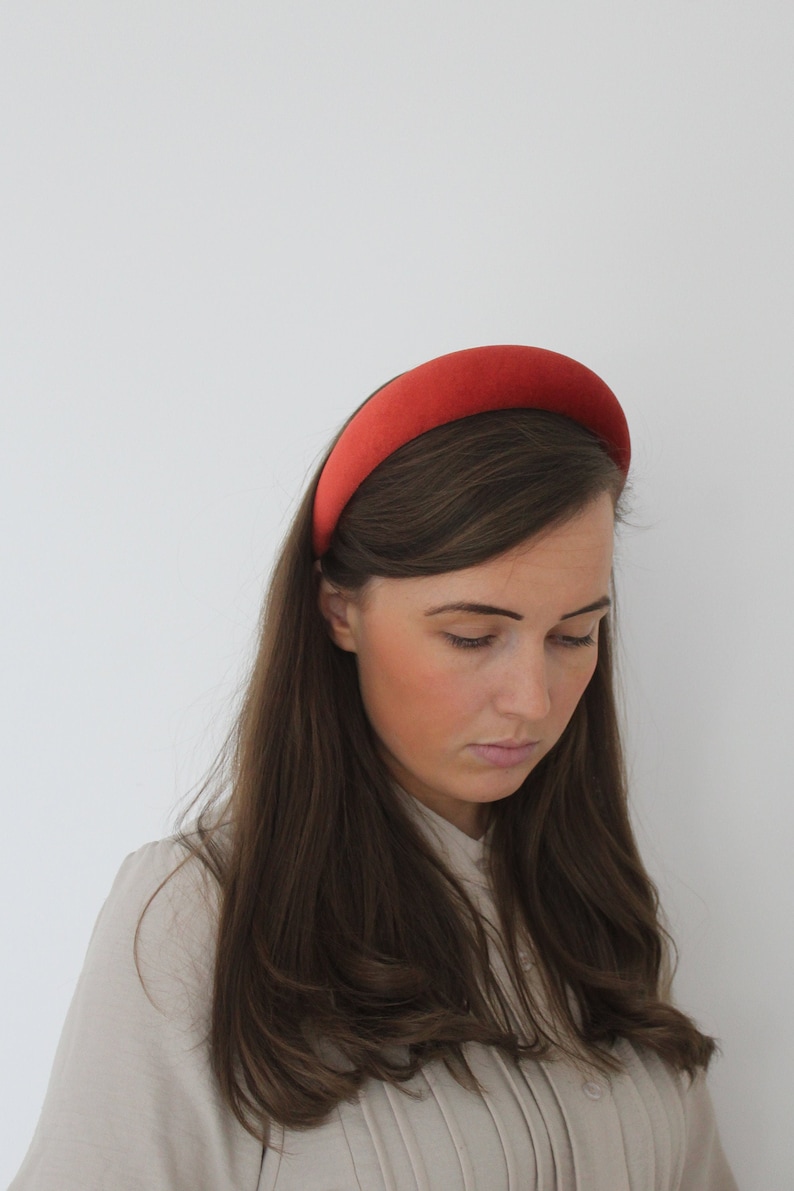 Puede incluir: Una mujer con el pelo largo y casta&ntilde;o lleva una diadema ancha de terciopelo rojo. Est&aacute; mirando hacia abajo y su pelo est&aacute; peinado en ondas sueltas.