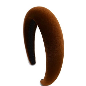 May include: A brown velvet headband with a wide, curved shape.