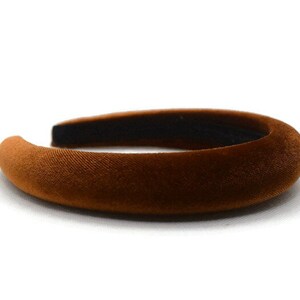 May include: A brown velvet headband. The headband is thick and wide, and it is made of a soft, plush material.