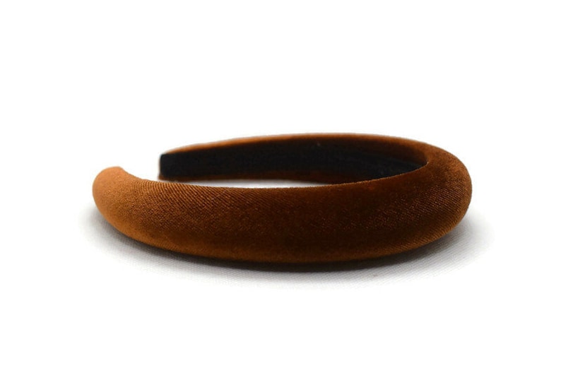 May include: A brown velvet headband. The headband is thick and wide, and it is made of a soft, plush material.