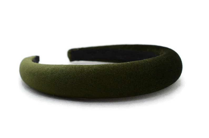May include: A wide, dark green velvet headband. The headband is thick and has a smooth, soft texture.