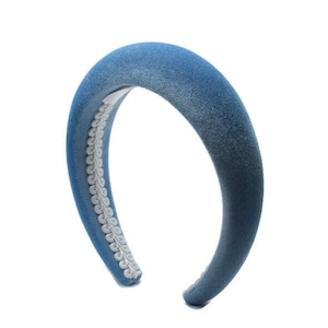 May include: A padded headband covered in blue denim fabric. The interior edge features a white, scalloped trim. The headband is a simple, yet stylish hair accessory.