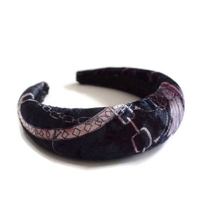May include: A black velvet headband with a pink and white chain print design.