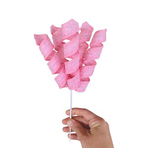 May include: A pink ribbon with a swirl design is attached to a white stick. The ribbon is curled and twisted to create a flower-like shape.
