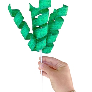 May include: A bunch of green curly ribbon with a white stem. The ribbon has a patterned design.
