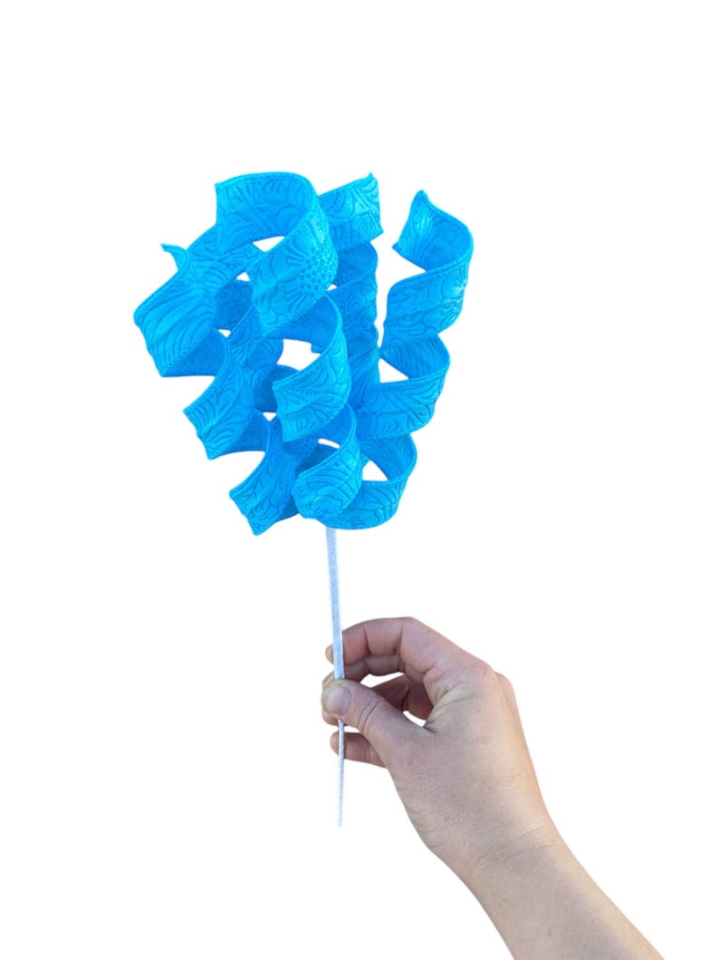 May include: A blue, curly, decorative flower with a white stem. The flower is made of plastic and has a textured surface.