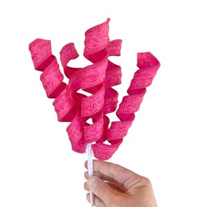 May include: A pink curly ribbon with a white stem. The ribbon has a floral pattern and is curled into a spiral shape.