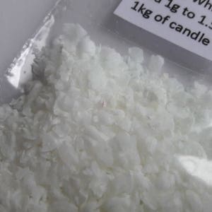 May include: White candle wax flakes in a clear plastic bag. The bag has a label that reads "White 1g to 1.5g per 1kg of candle wax".