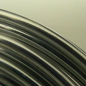 Op de afbeelding: Close-up van een zilveren draadspiraal, die het glanzende, metalen oppervlak en de ronde vorm van de draad laat zien.