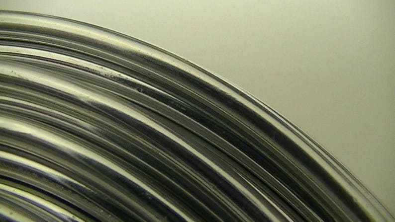 Op de afbeelding: Close-up van een zilveren draadspiraal, die het glanzende, metalen oppervlak en de ronde vorm van de draad laat zien.