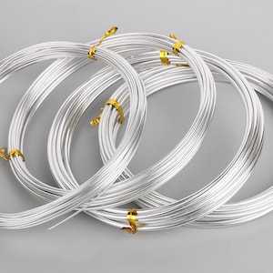 May include: Spools of silver-coloured wire, wrapped with gold tape, for jewellery making or crafting.