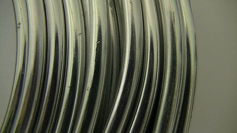 Op de afbeelding: Close-up van een bundel zilverkleurige metaaldraad. De draad is opgerold en heeft een gladde, glanzende afwerking.