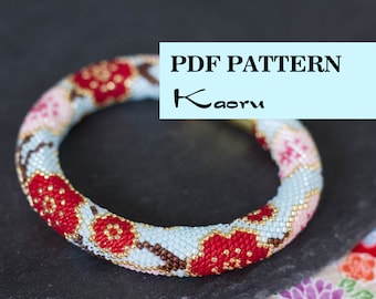 Puede incluir: Patrón PDF para un brazalete de cuentas con un diseño de flor de cerezo. El brazalete está hecho con cuentas rojas, rosas, azules, marrones y doradas. El patrón es de Kaoru.