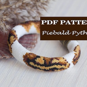 Puede incluir: Un brazalete de cuentas con fondo blanco y patrones marrones y amarillos, que se asemeja a una pitón piebald. El brazalete está sobre una superficie blanca con una concha y flores secas en el fondo. El texto "PDF PATTERN Piebald Python" se muestra en un rectángulo marrón.
