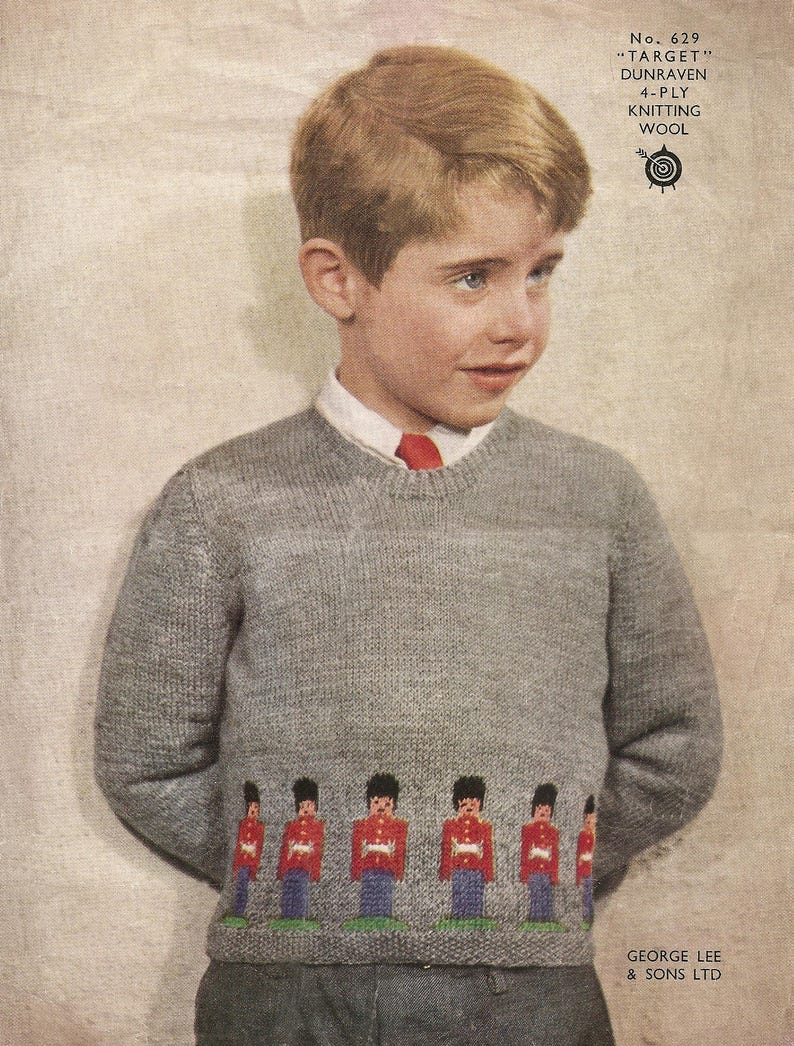 Puede incluir: Un ni&ntilde;o peque&ntilde;o con un su&eacute;ter de punto gris con una fila de soldados de juguete bordados en la parte inferior. El su&eacute;ter tiene un cuello rojo y una corbata roja. El ni&ntilde;o tiene el pelo rubio corto y mira hacia la derecha. El texto "No. 629 "TARGET" DUNRAVEN 4-PLY KNITTING WOOL" est&aacute; impreso en la esquina superior derecha de la imagen.