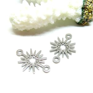 Peut inclure: Deux connecteurs de bijoux en métal argenté, chacun présentant une découpe circulaire centrale entourée de rayons pointus rayonnants et deux petites boucles circulaires positionnées aux extrémités opposées pour la fixation.