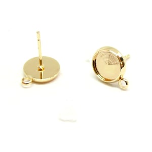 Peut inclure: Deux clous d'oreilles dorés avec des montures rondes et de petites boucles. Les clous sont conçus pour la fabrication de bijoux, avec une base en forme de disque plat et une tige pour l'insertion. Les montures ont une zone encastrée pour fixer des éléments décoratifs.