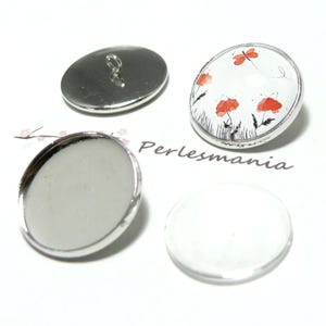 Puede incluir: Cuatro botones ovalados. Uno tiene una parte trasera plateada con un lazo, otro tiene una cara blanca con ilustraciones de flores rojas, y dos son de color plateado con una cara en blanco. El texto "Perlesmania" es visible.