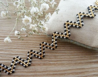 woven bracelet in the shape of a zig zag black ecru gold graphic boho inspiration