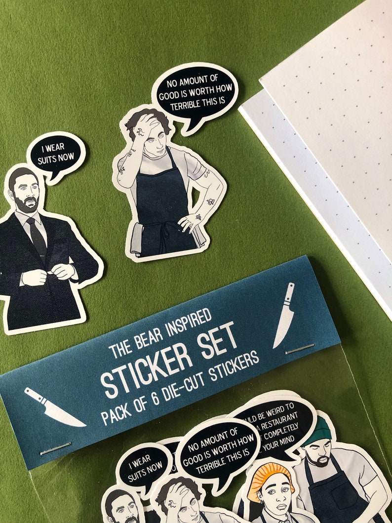 K&ouml;nnte beinhalten: Ein Set mit sechs Stanzaufklebern mit Figuren und Zitaten aus der TV-Serie "The Bear". Die Aufkleber sind in einer durchsichtigen Plastikt&uuml;te mit einer blauen Kopfzeile verpackt, auf der "The Bear Inspired Sticker Set" steht.